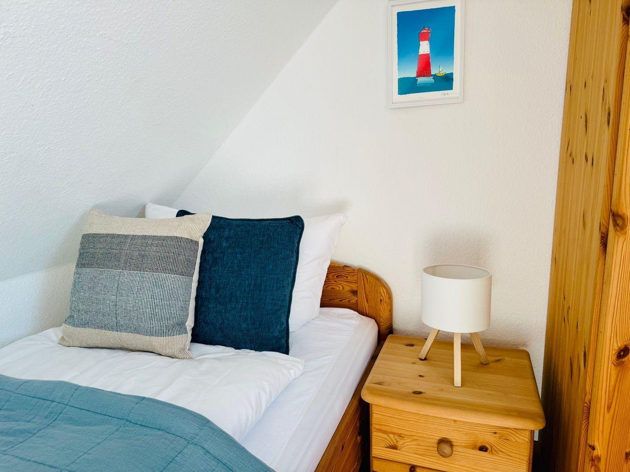 Schlafzimmer mit Bett, Nachttisch und Bild an der Wand.