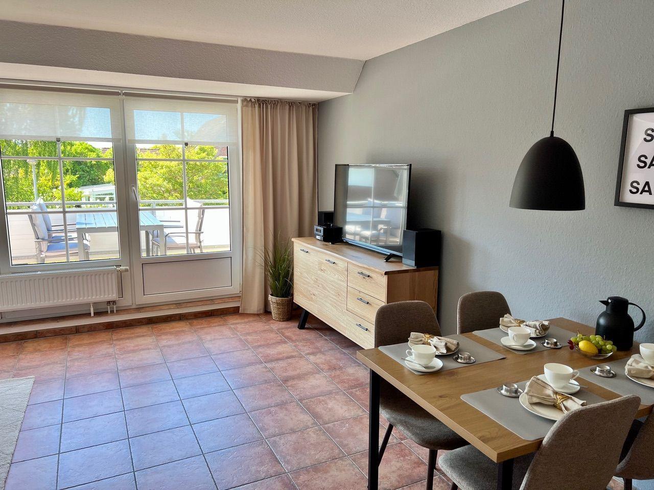 Esszimmer mit Tisch, Stühlen und Fernseher. Terrasse mit Gartenblick.