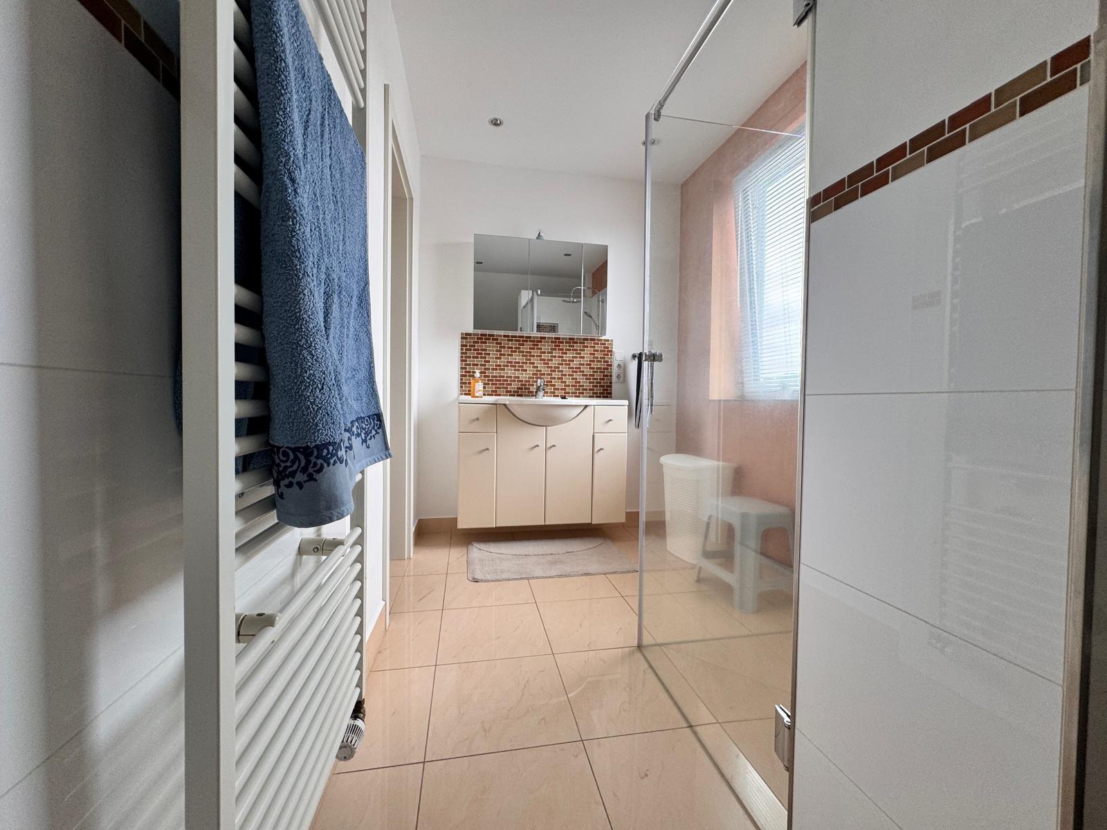 Badezimmer mit Dusche, Waschbecken und Heizkörper