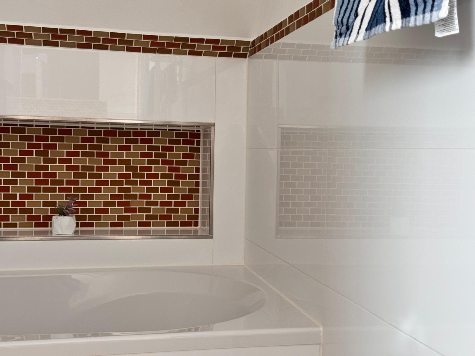 Bad mit weißer Badewanne und farbigen Fliesen an der Wand.