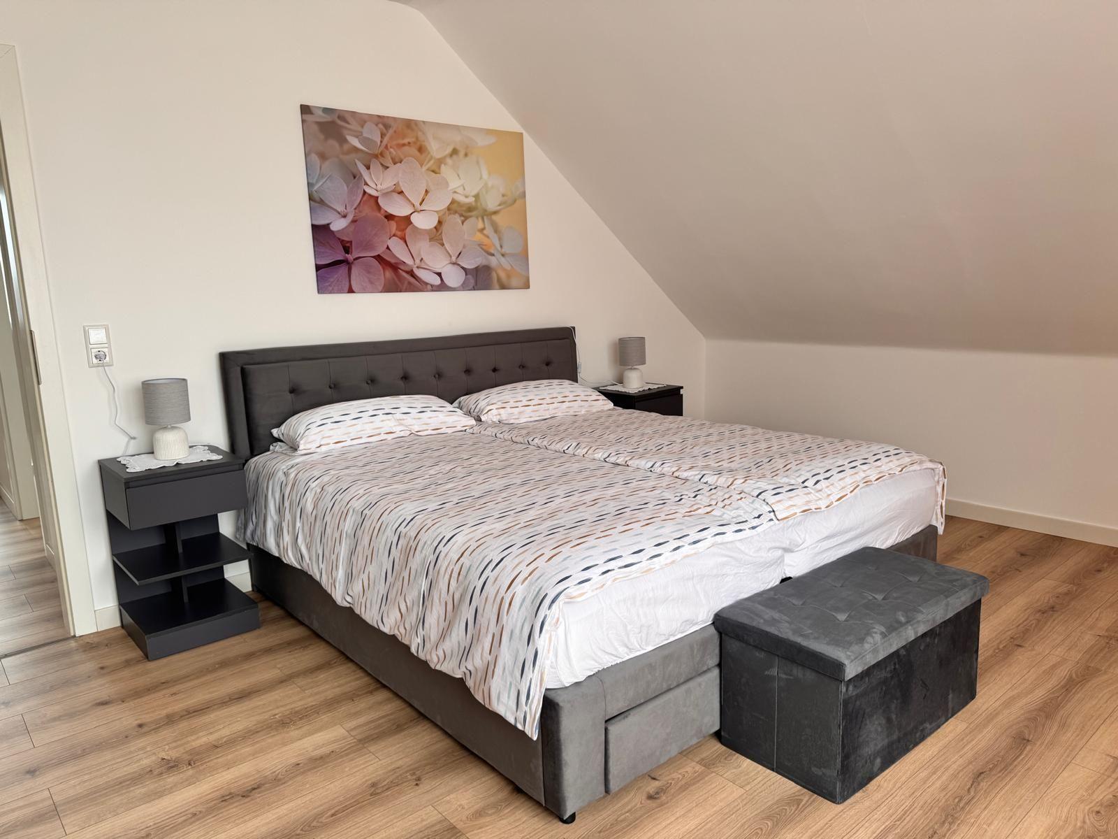 Schlafzimmer mit Doppelbett, Nachttischen und Wandbild