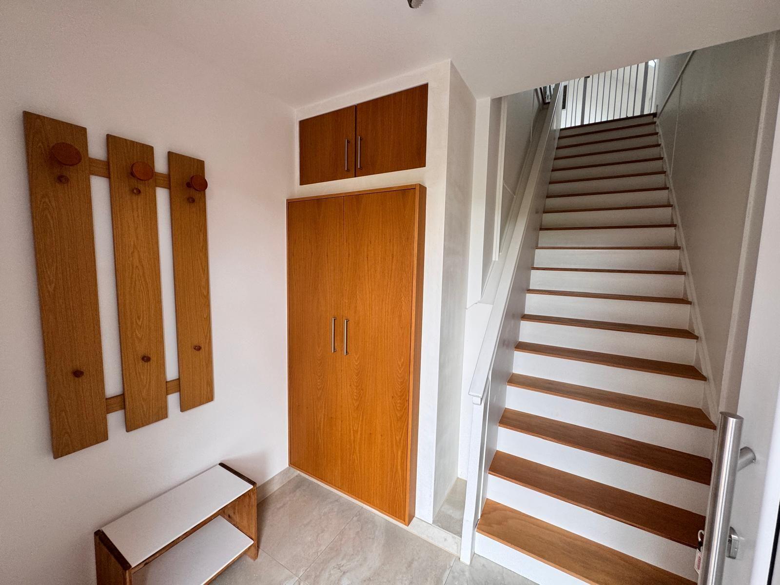 Eingang mit Holzgarderobe, Schuhschrank und Treppe nach oben.