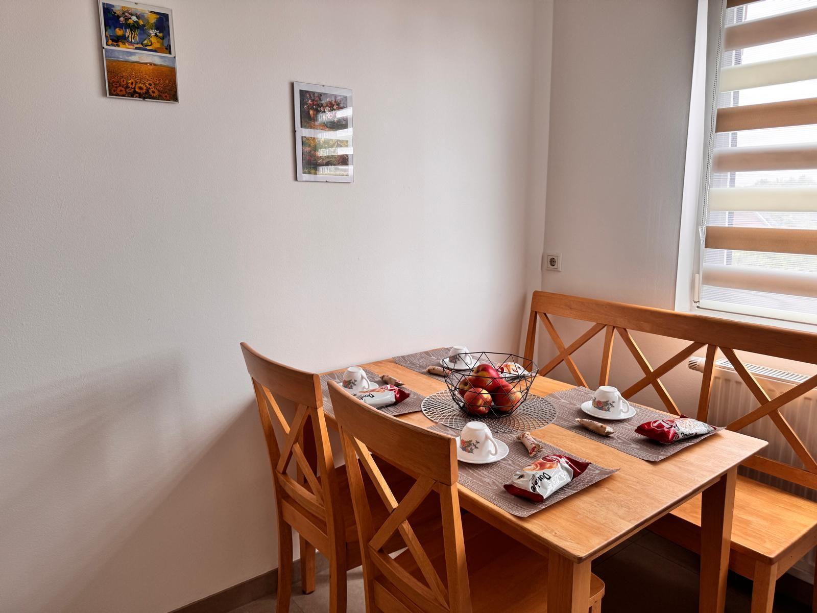 Holztisch mit Stühlen und Fensterbank. Tisch gedeckt mit Obst und Snacks.
