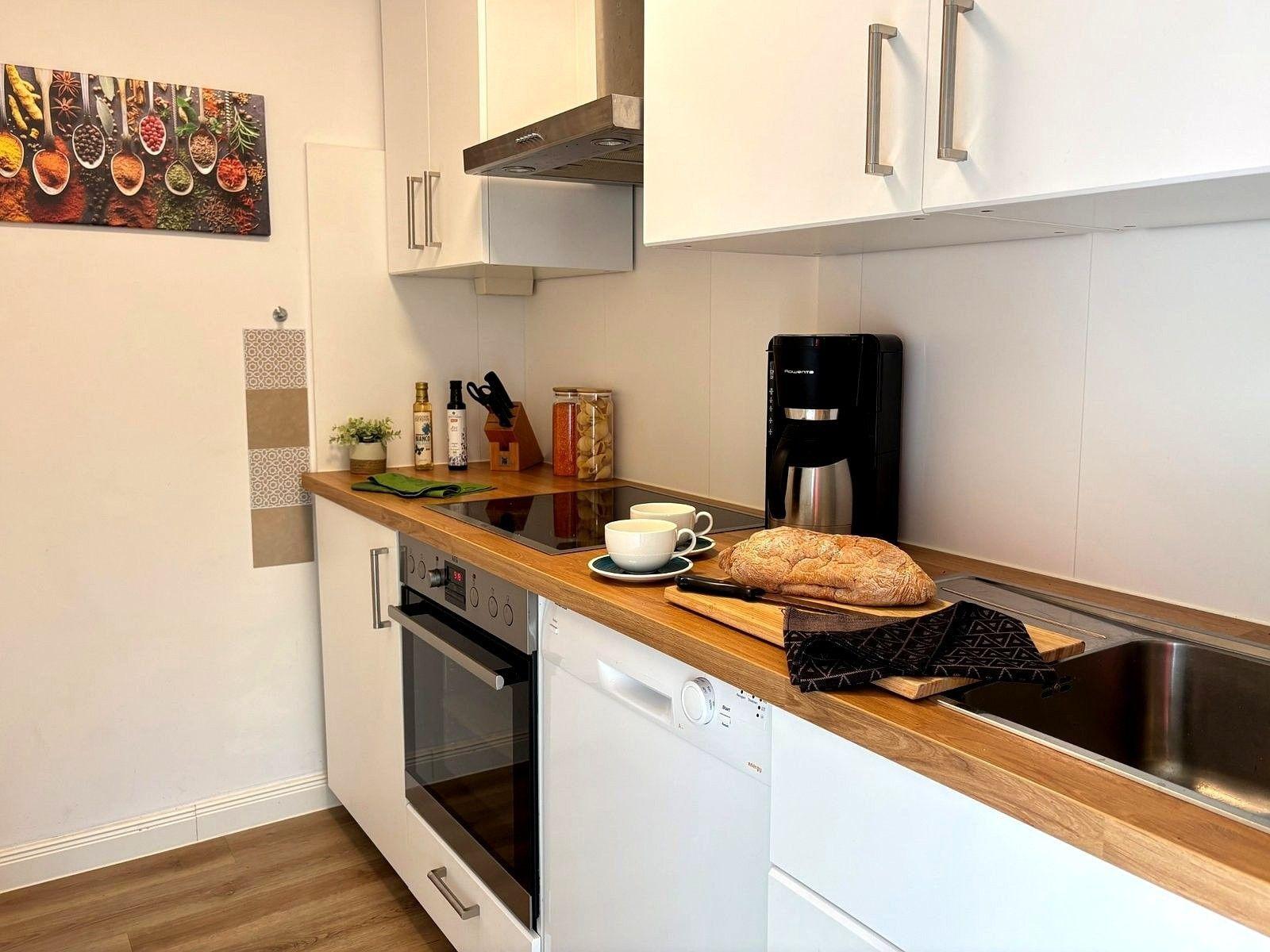 Küche mit Holzoberfläche, Spüle, Kaffeemaschine und Backofen
