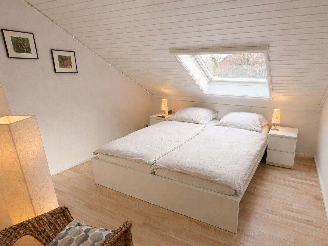 Schlafzimmer mit Doppelbett, Dachschrägen, Dachfenster und zwei Nachttischen.