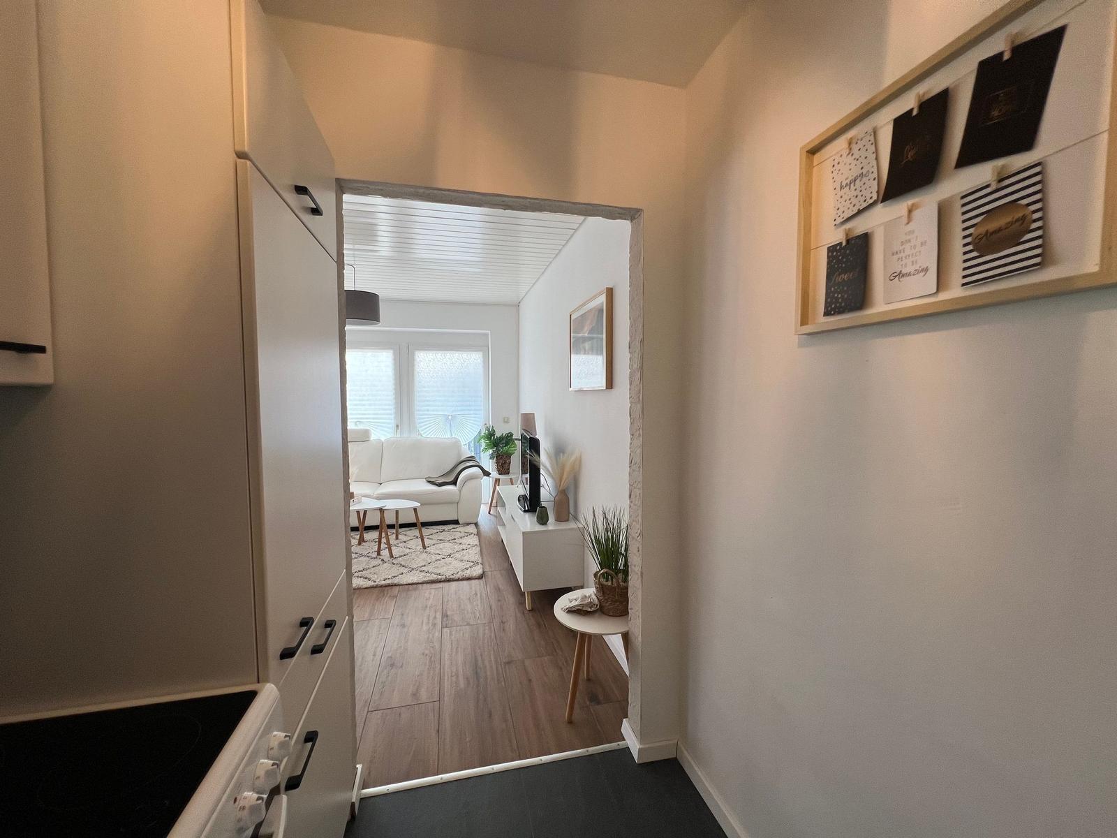 Küche mit Blick in Wohnzimmer mit Sofa und TV.