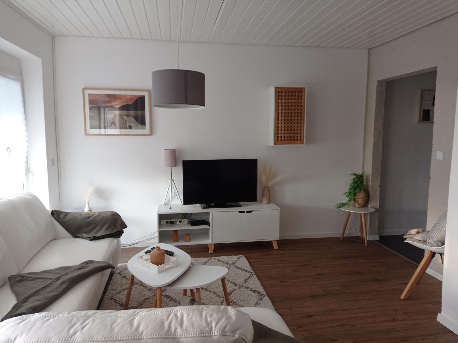 Wohnzimmer mit weißem Sofa, TV-Möbel und Holzboden.