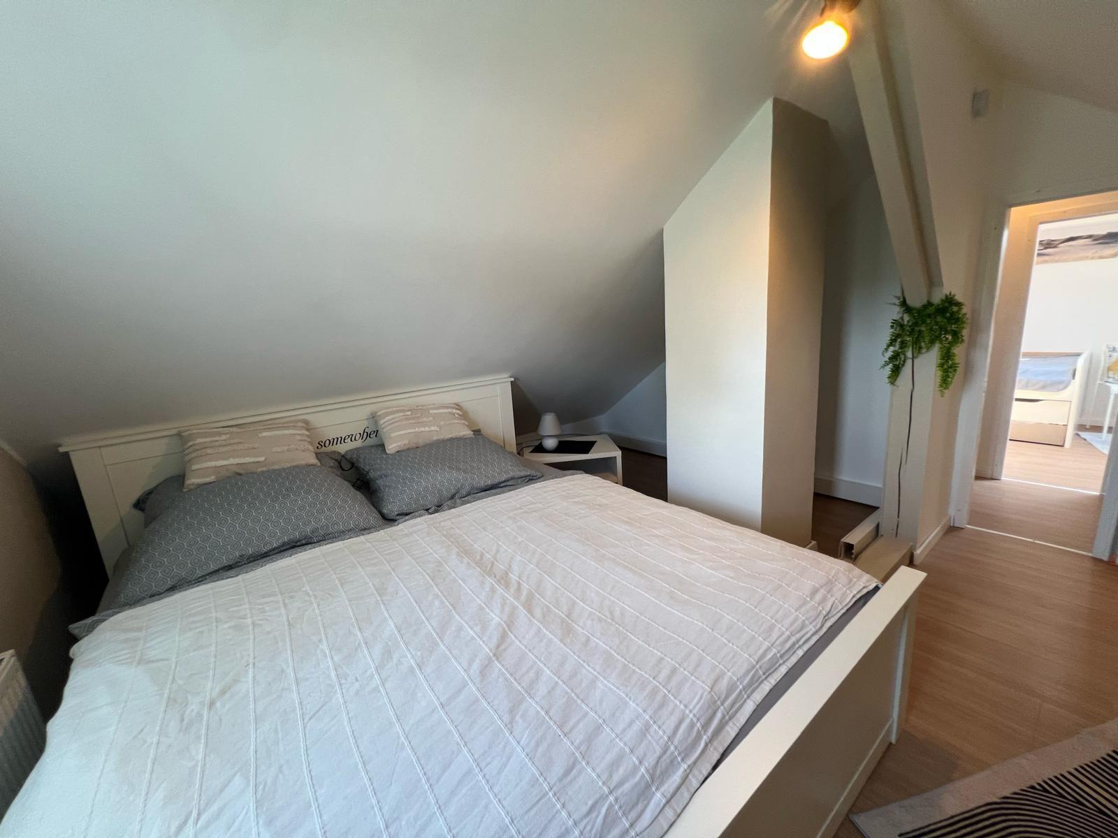 Schlafzimmer mit Dachschräge, Bett und Nachttisch