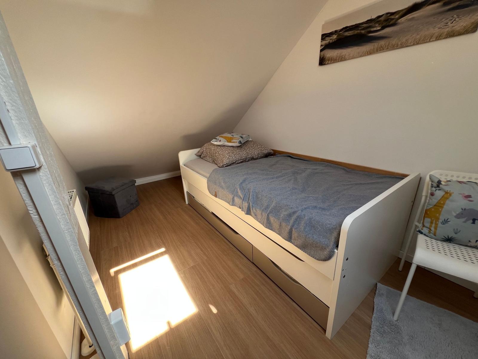 Schlafzimmer mit Dachschrägen, Bett und Stuhl.