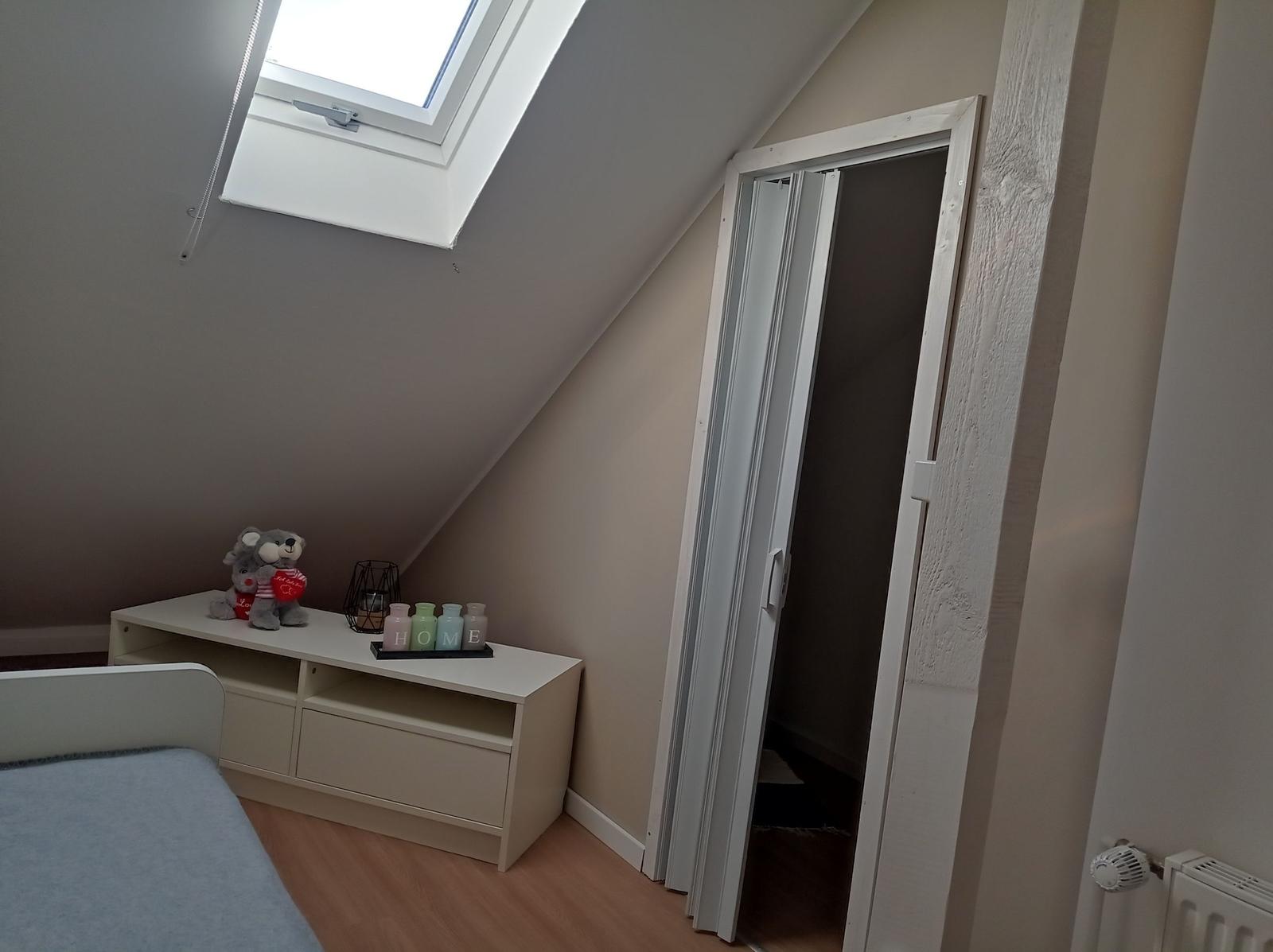 Schlafzimmer mit Dachschräge, Dachfenster und Kleiderschrank.
