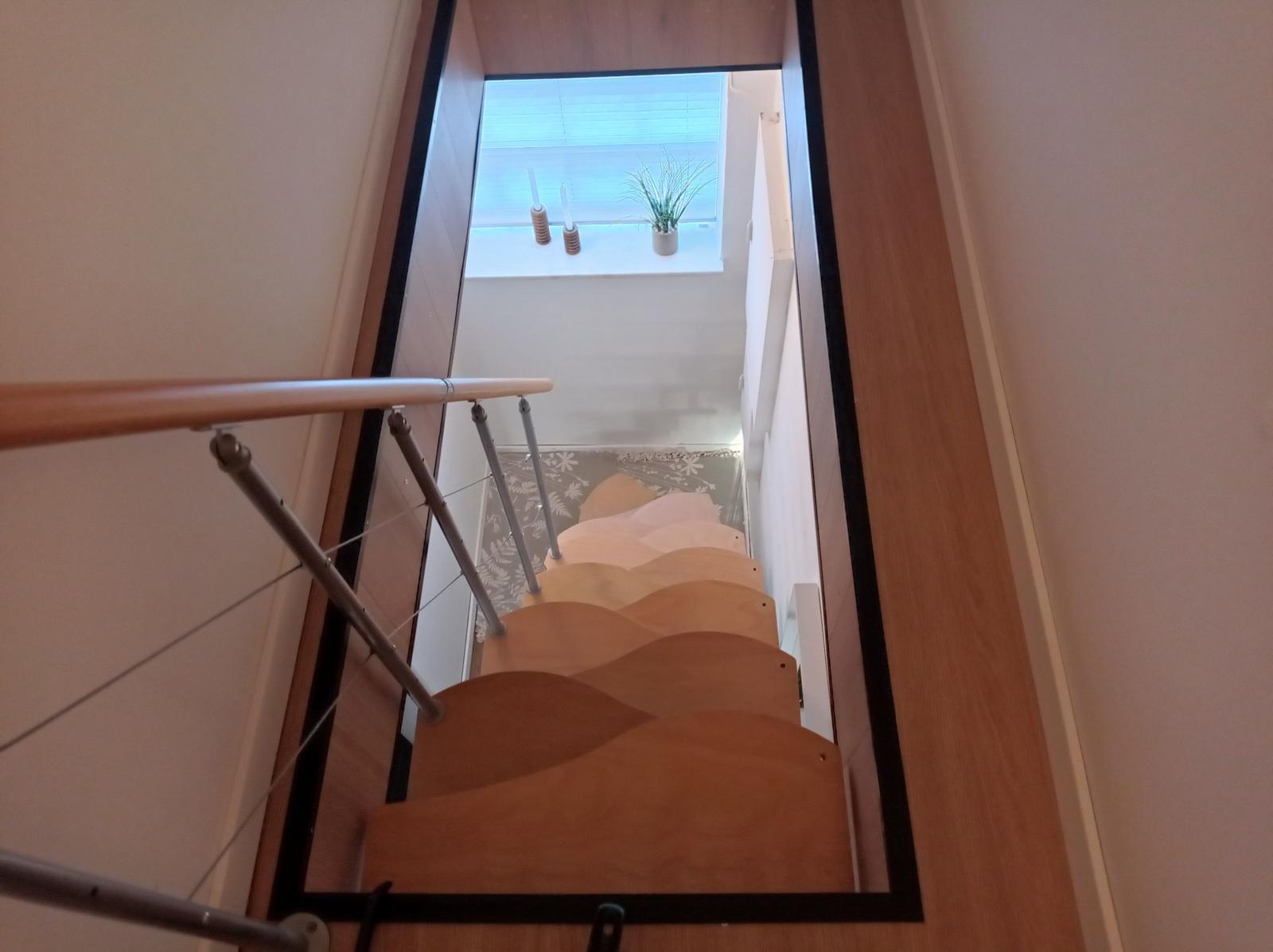 Holzstufen führen nach oben. Fenster mit Pflanze und Dekoration.