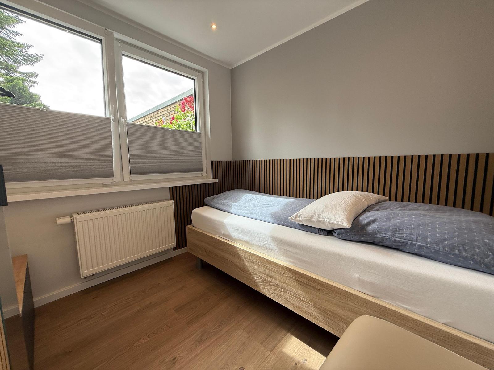 Ein Schlafzimmer mit Bett, Fenster und Holzboden.