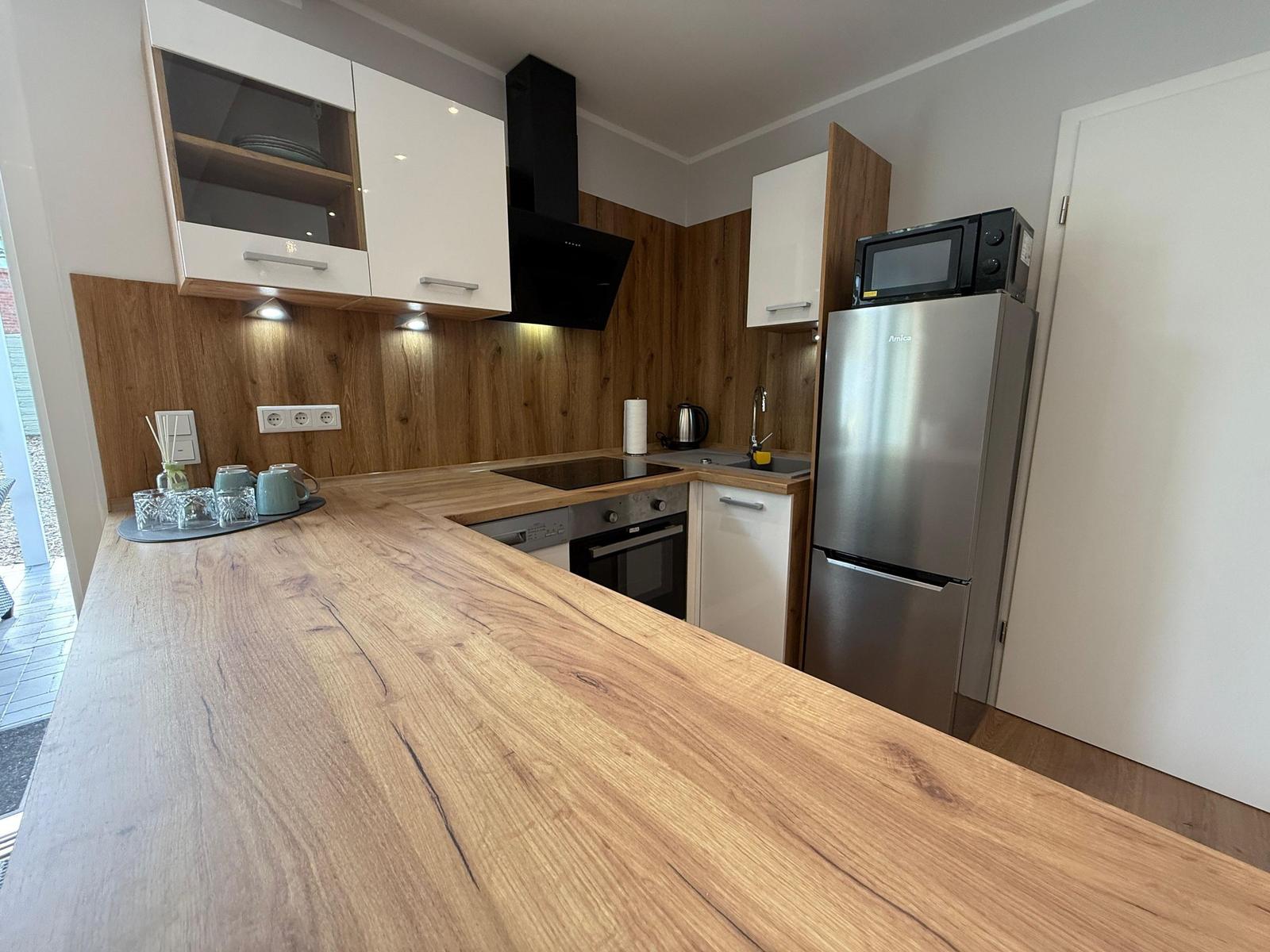 Moderne Küche mit Holzoberfläche, Kühlschrank und Dunstabzug.