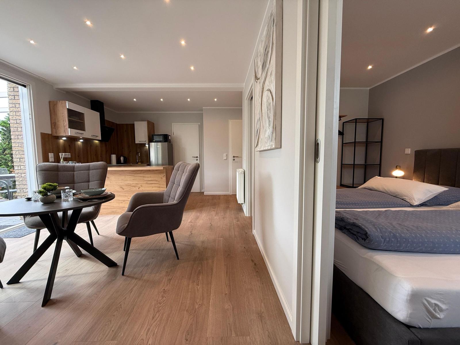 Wohnbereich mit Essbereich und Küche. Nebenraum mit Schlafzimmer und Bett.