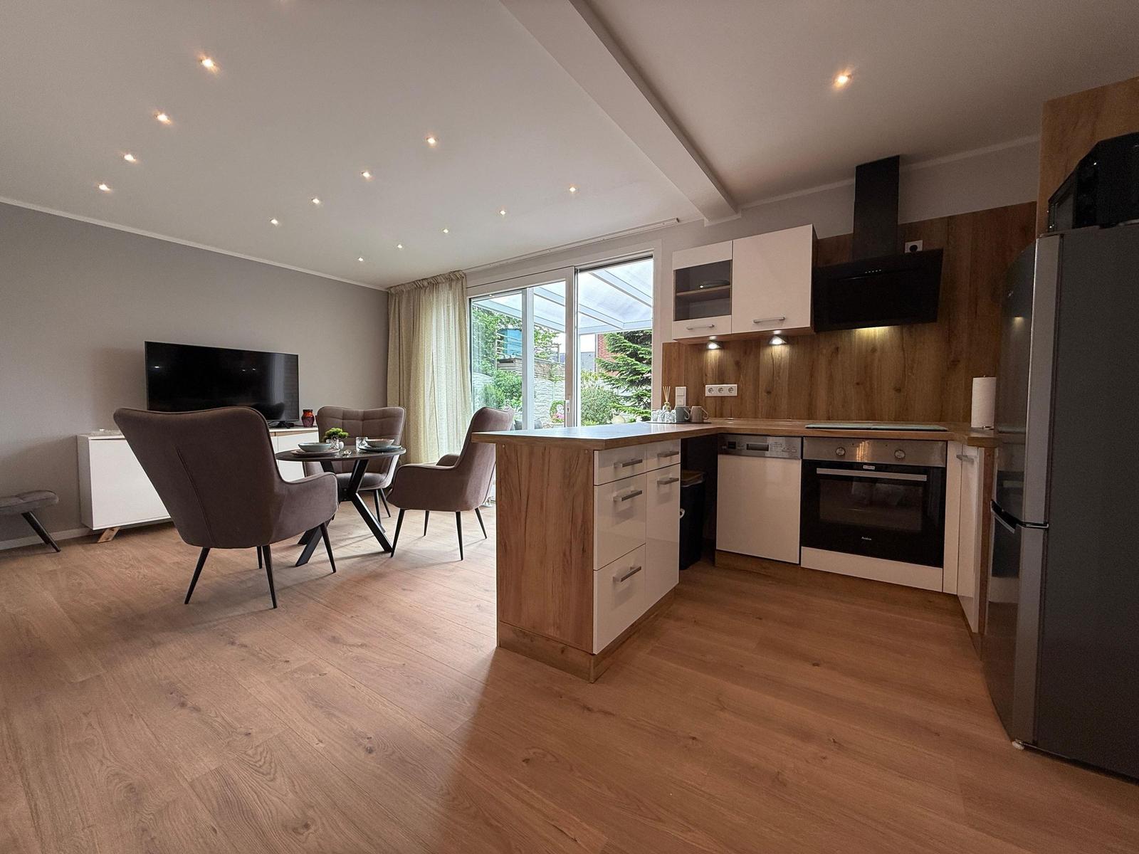 Moderne Küche mit Essbereich und Fernseher. Holzfußboden und großes Fenster.