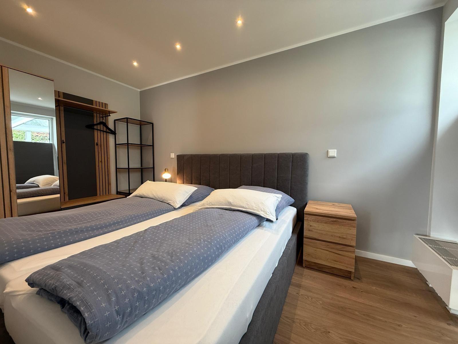 Schlafzimmer mit Doppelbett, Nachttisch und Kleiderschrank.