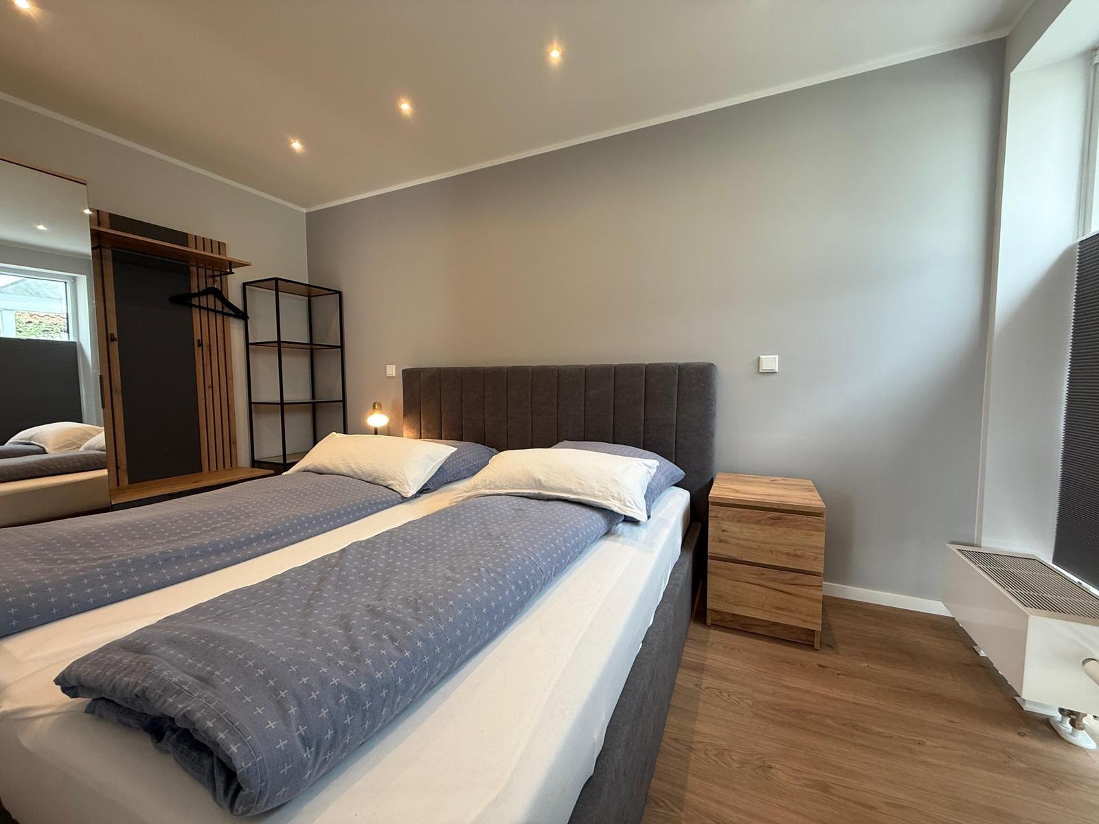 Schlafzimmer mit Doppelbett, Nachttisch und Kleiderschrank.
