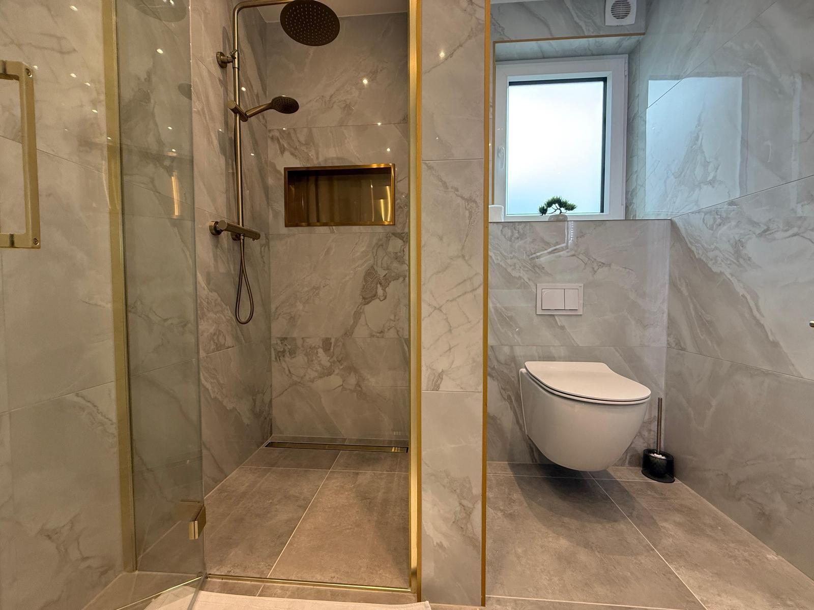 Dusche mit Glaswand und Toilette in Marmoroptik