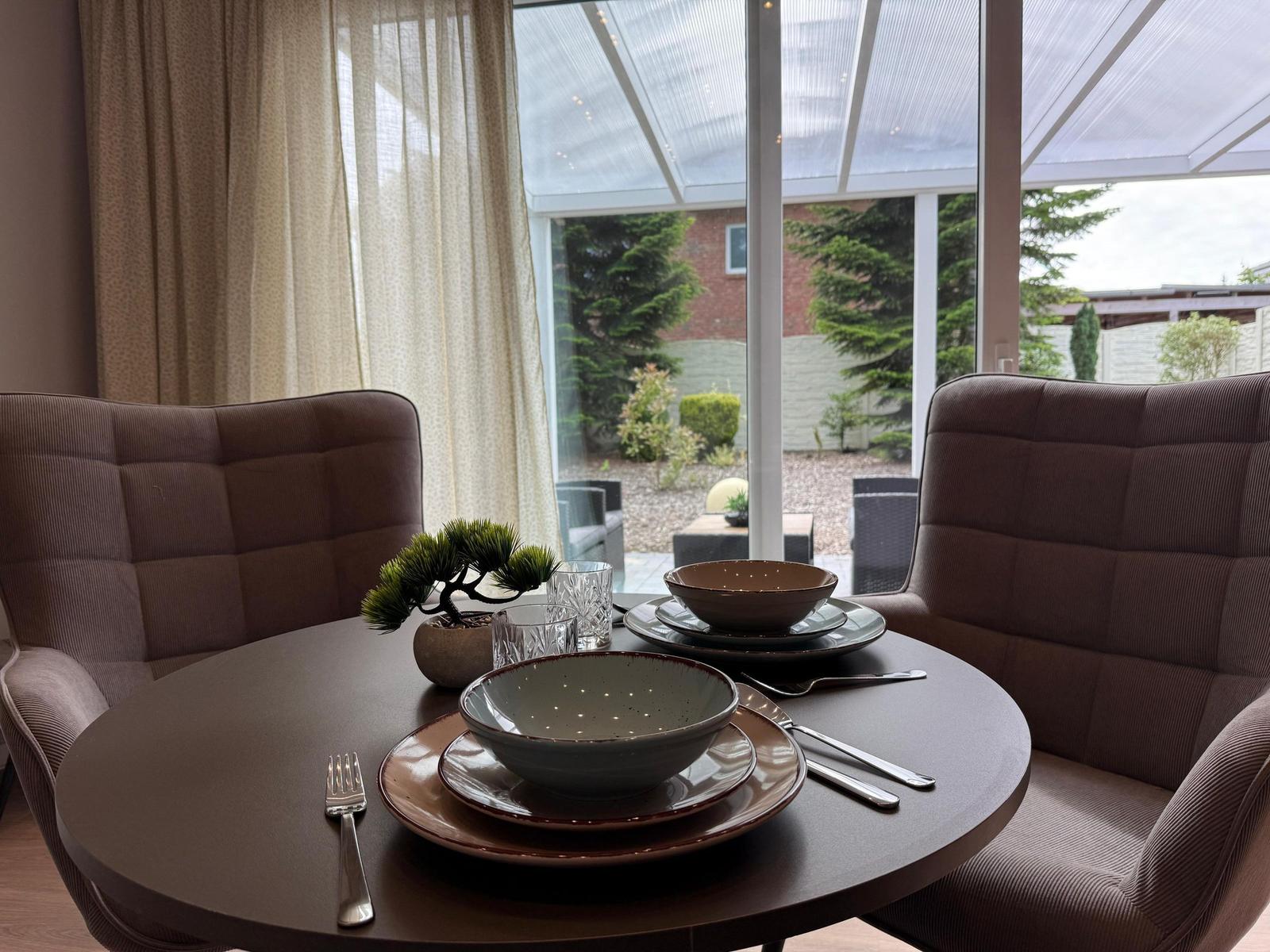 Rundtisch mit zwei Stühlen, gedeckt, Blick auf Garten.