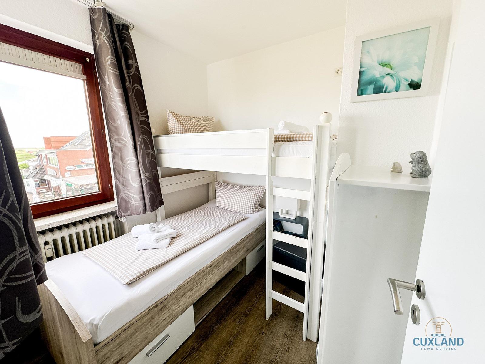 Zimmer mit Doppelstockbett, Fenster und Kleiderschrank.