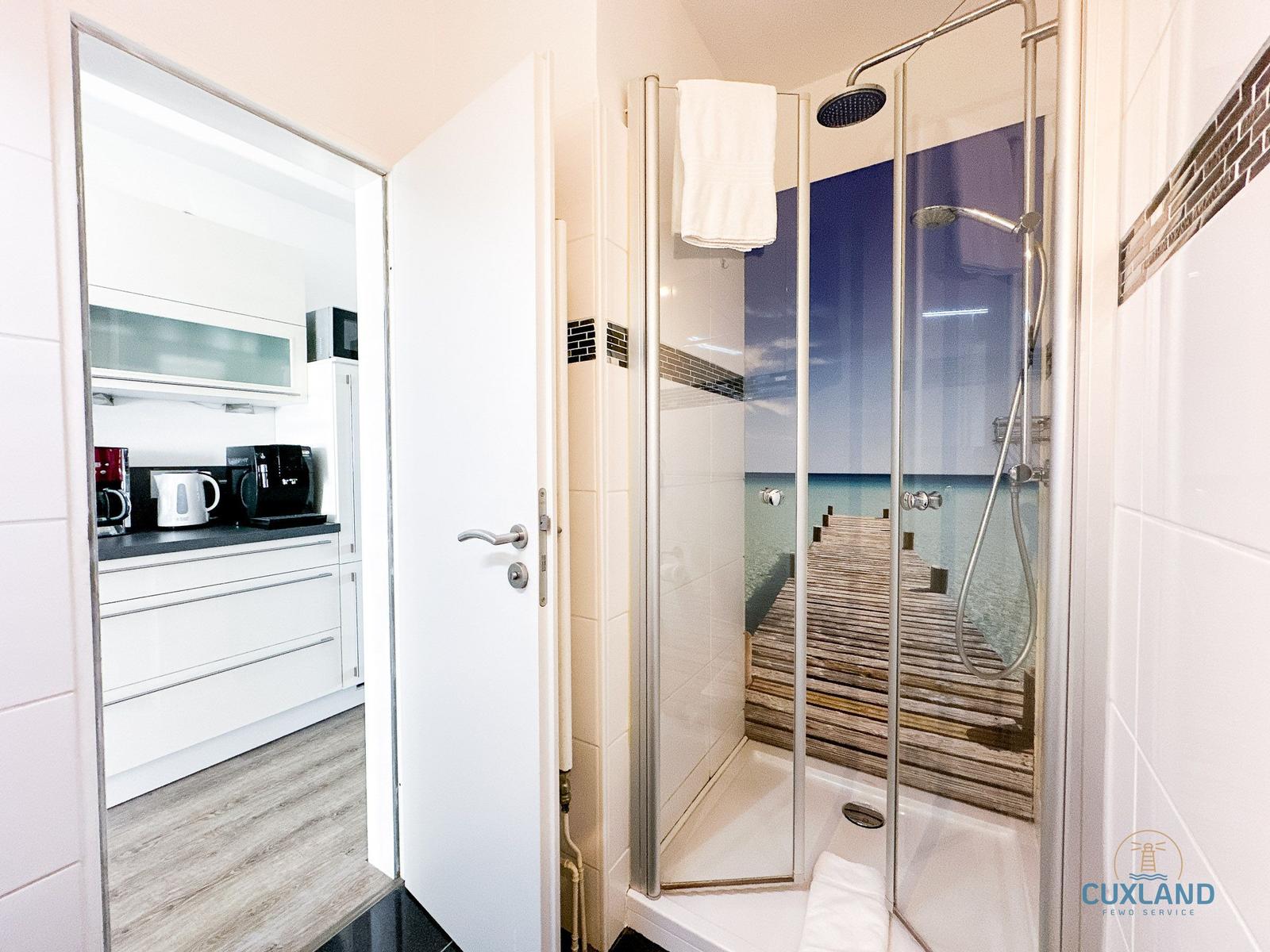 Dusche mit Meerblick-Tapete und angrenzende Küche mit Küchenschränken.