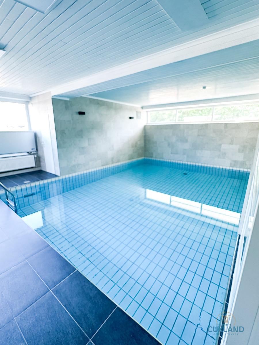 Innenpool mit blauen Fliesen und hellen Wänden