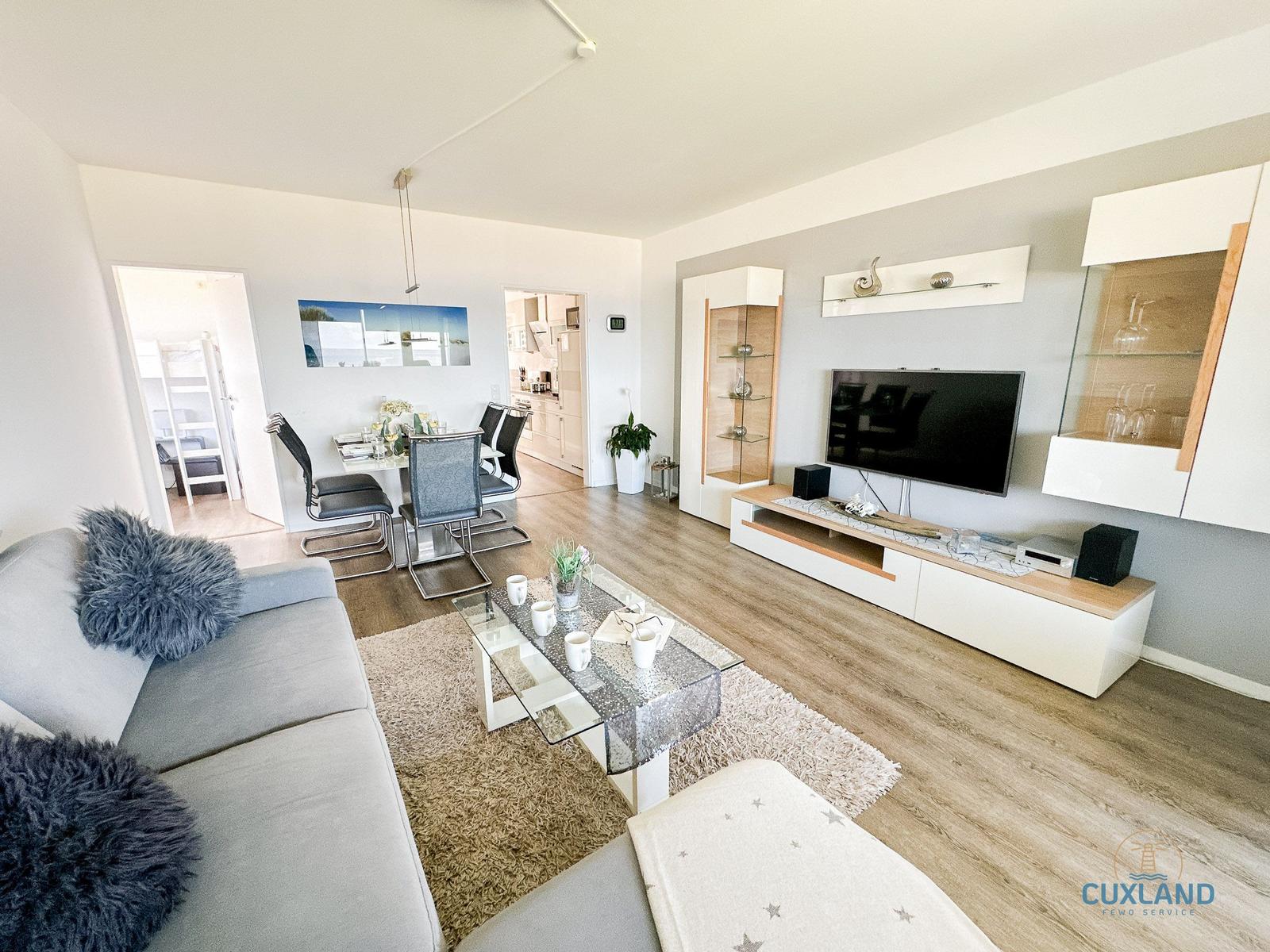 Wohn- und Essbereich mit Sofa, Fernseher und Glaswand.