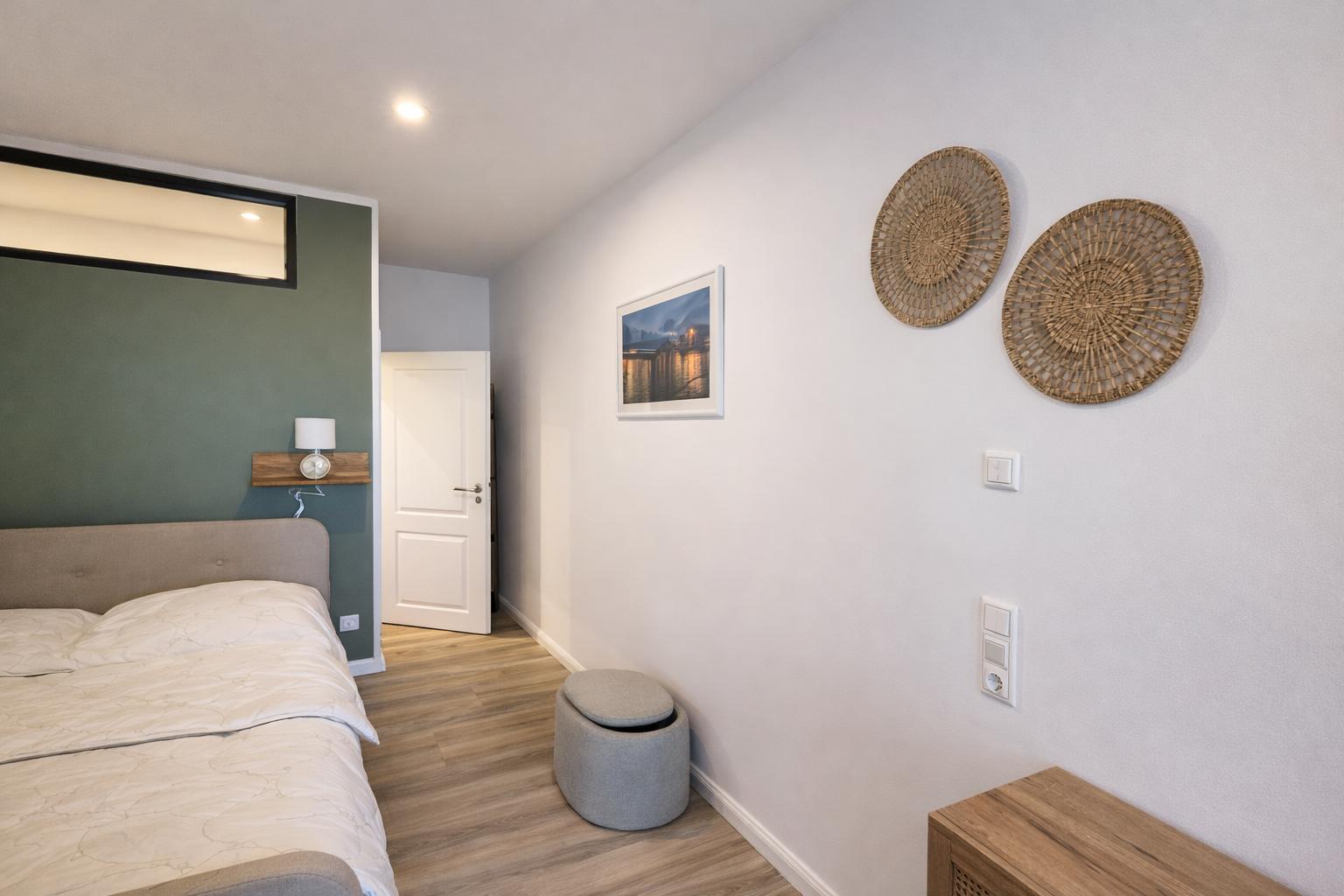 Schlafzimmer mit Bett, Wanddekoration und Holzboden.