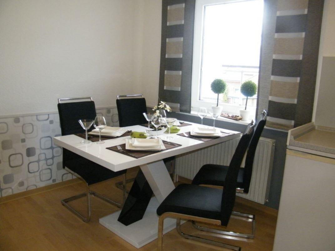 Esszimmer mit Tisch, Stühlen und Fenster. Wand mit Muster, Boden aus Holz.