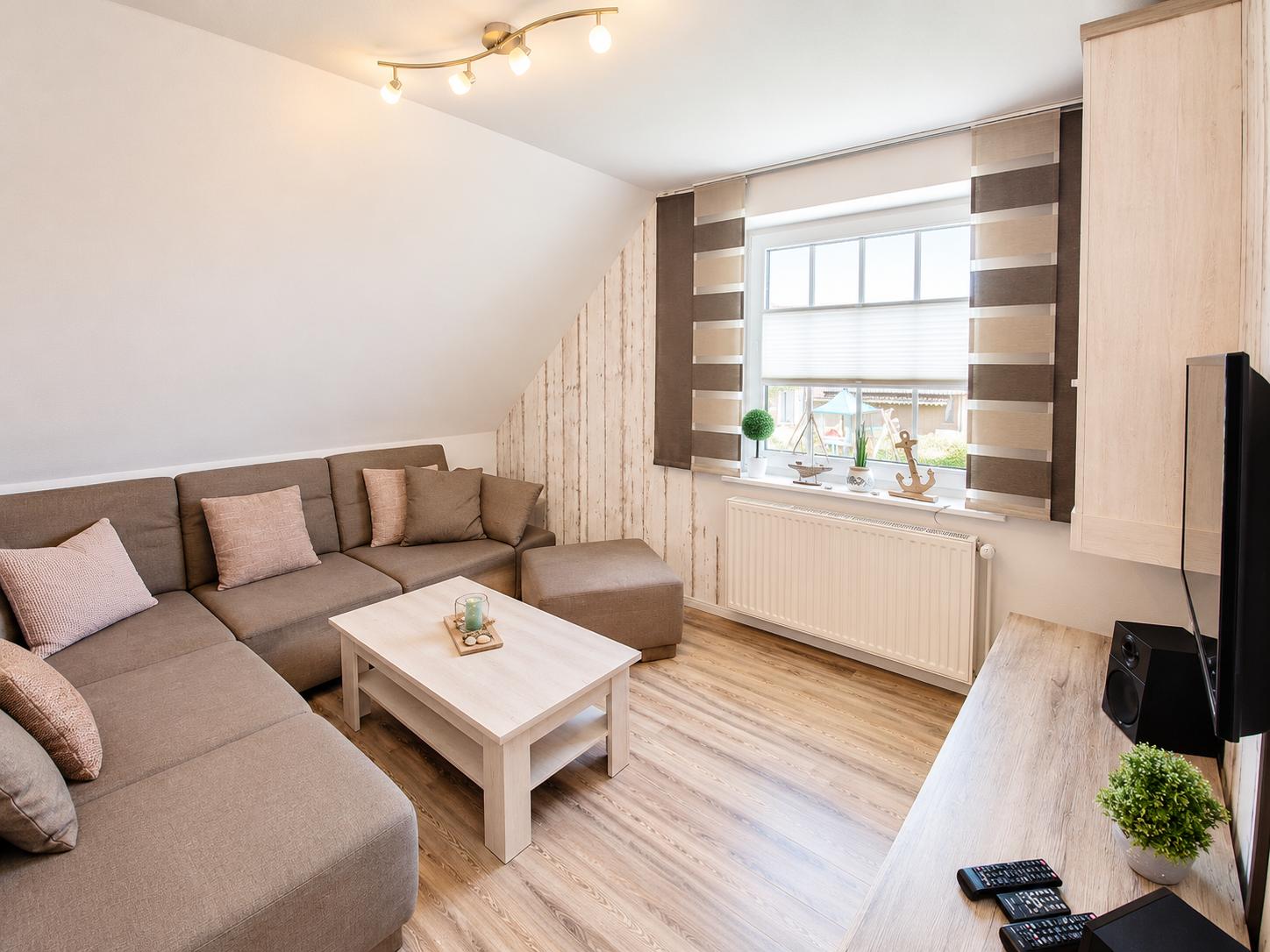 Wohnzimmer mit Sofa, Couchtisch und Fenster mit Jalousie.