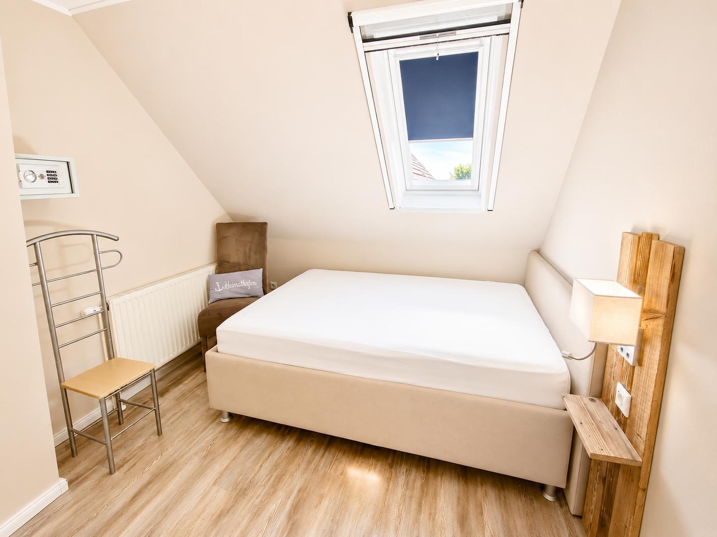Schlafzimmer mit Dachschrägen, Bett, Fenster und Holzboden.