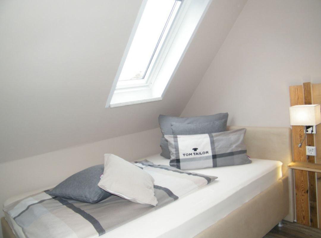 Schlafzimmer mit Dachschrägen, Dachfenster und Bett mit Kissen.