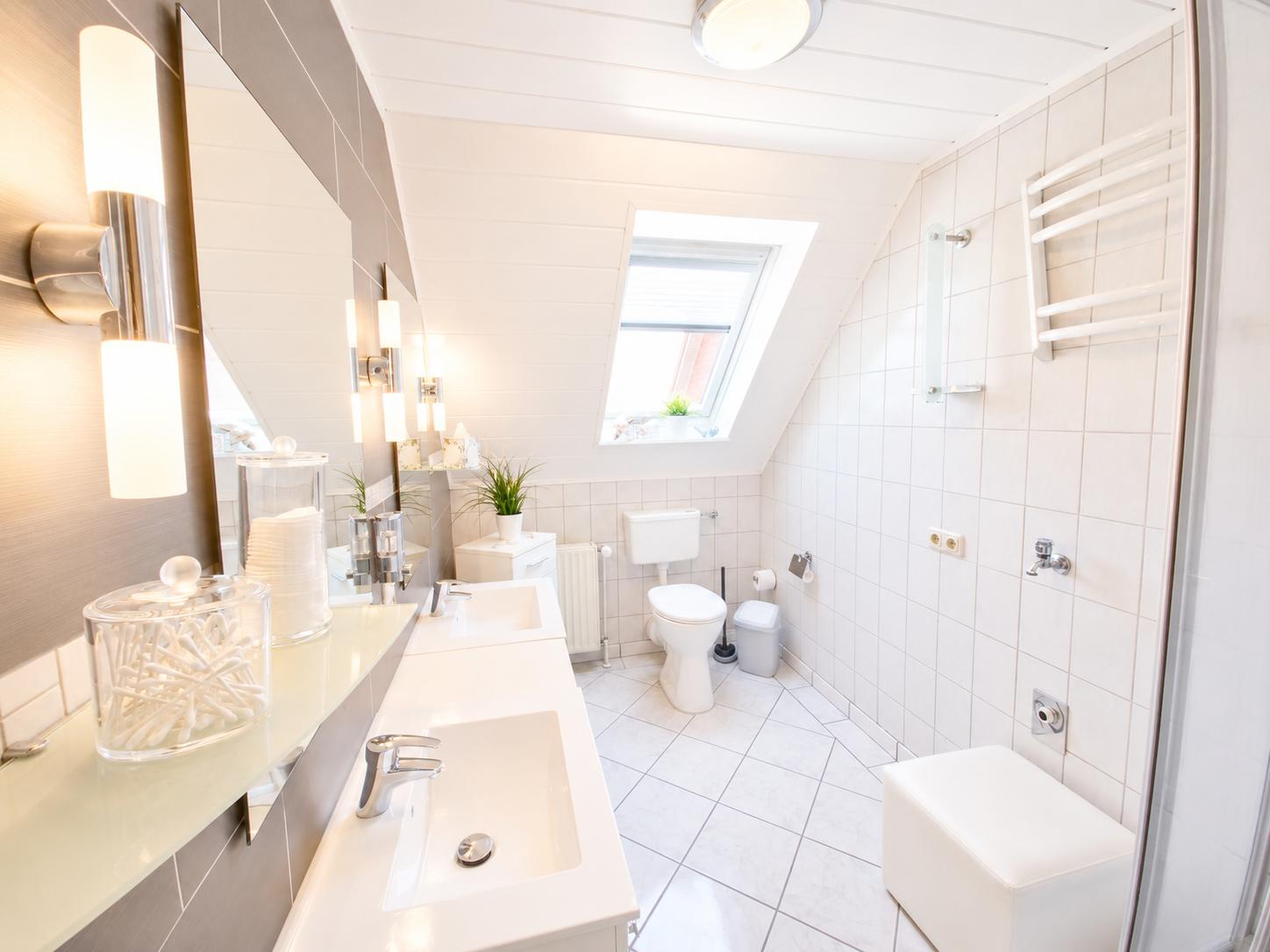 Badezimmer mit Dusche, Toilette und Waschbecken unter Dachschrägen.