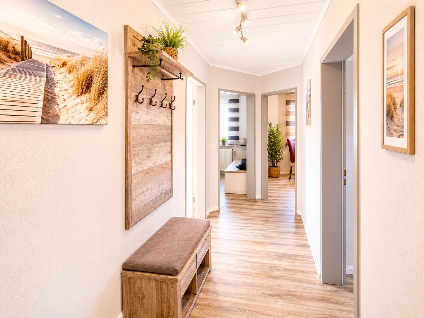 Flur mit Holzboden, Wandgarderobe und Sitzbank. Bilder an den Wänden.