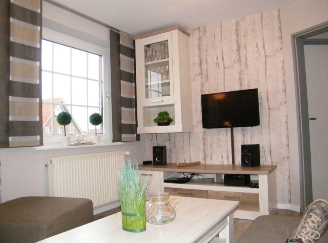 Wohnzimmer mit Fernseher, Glasvitrine und Fenster mit Blick.