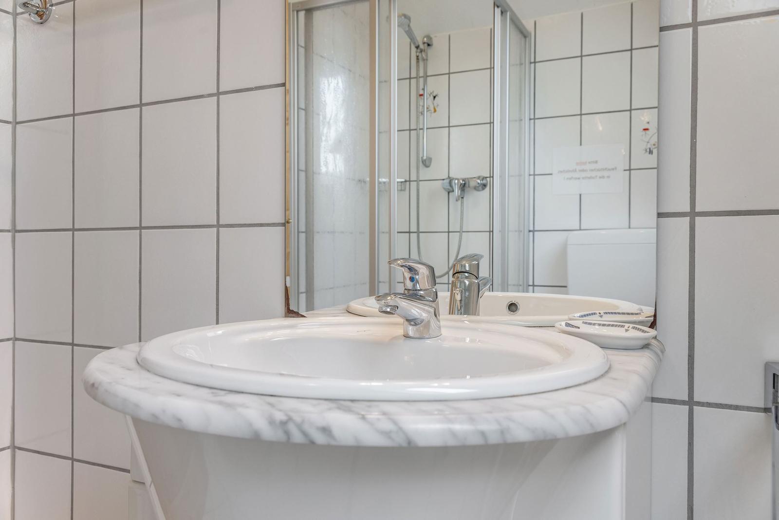 Badezimmer mit Waschbecken, Spiegel und Dusche.
