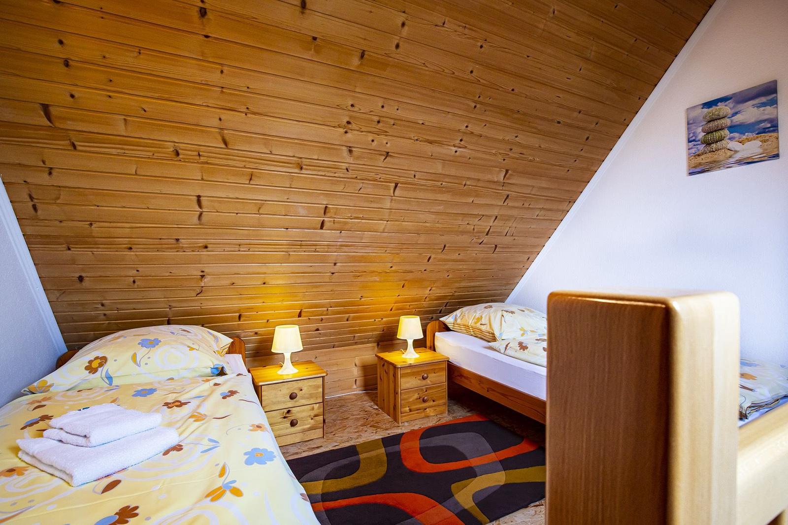 Zwei Betten mit Nachttischen und Lampen unter Holzdecke