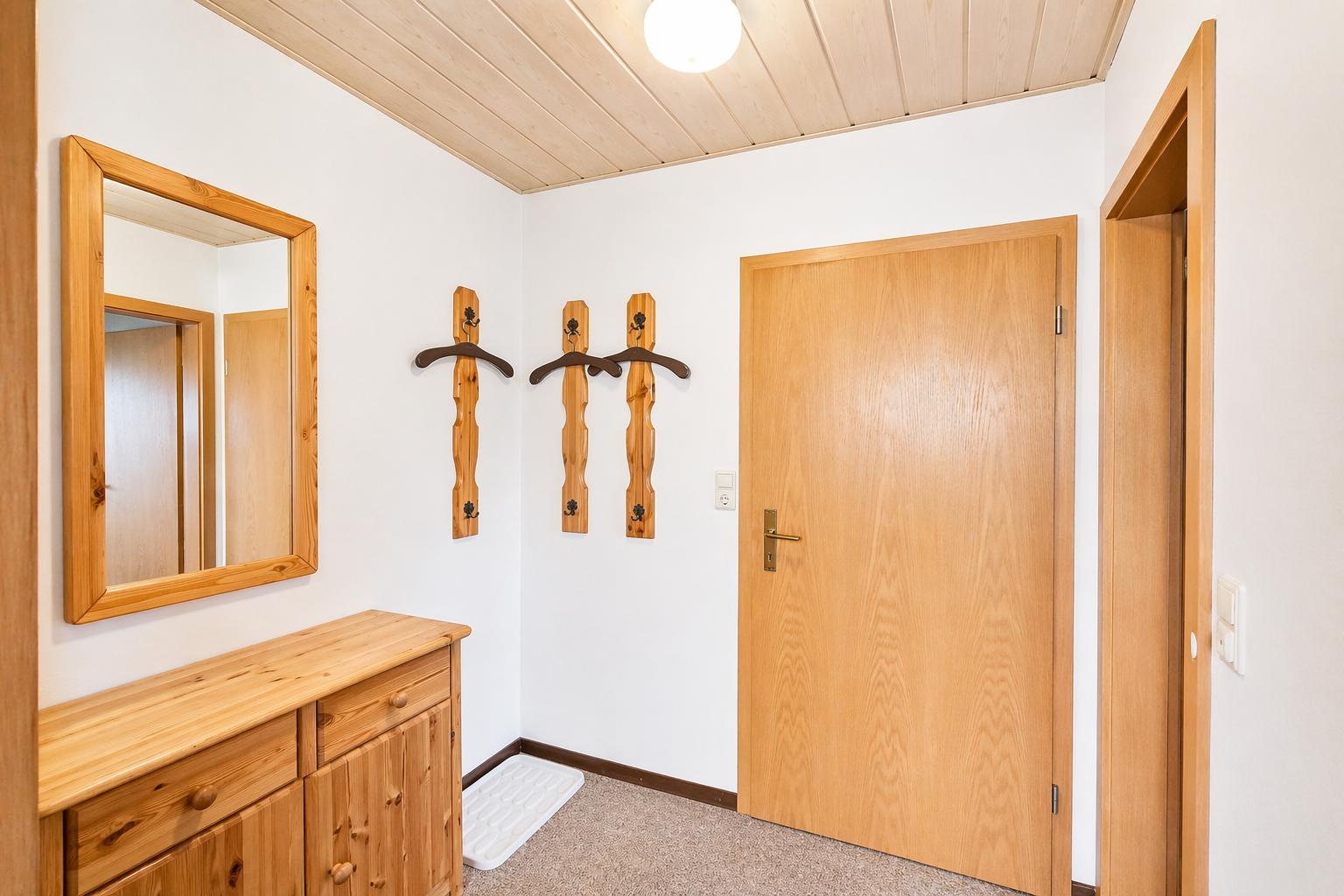 Eingangsbereich mit Holzschrank, Spiegel und Wandhalterungen