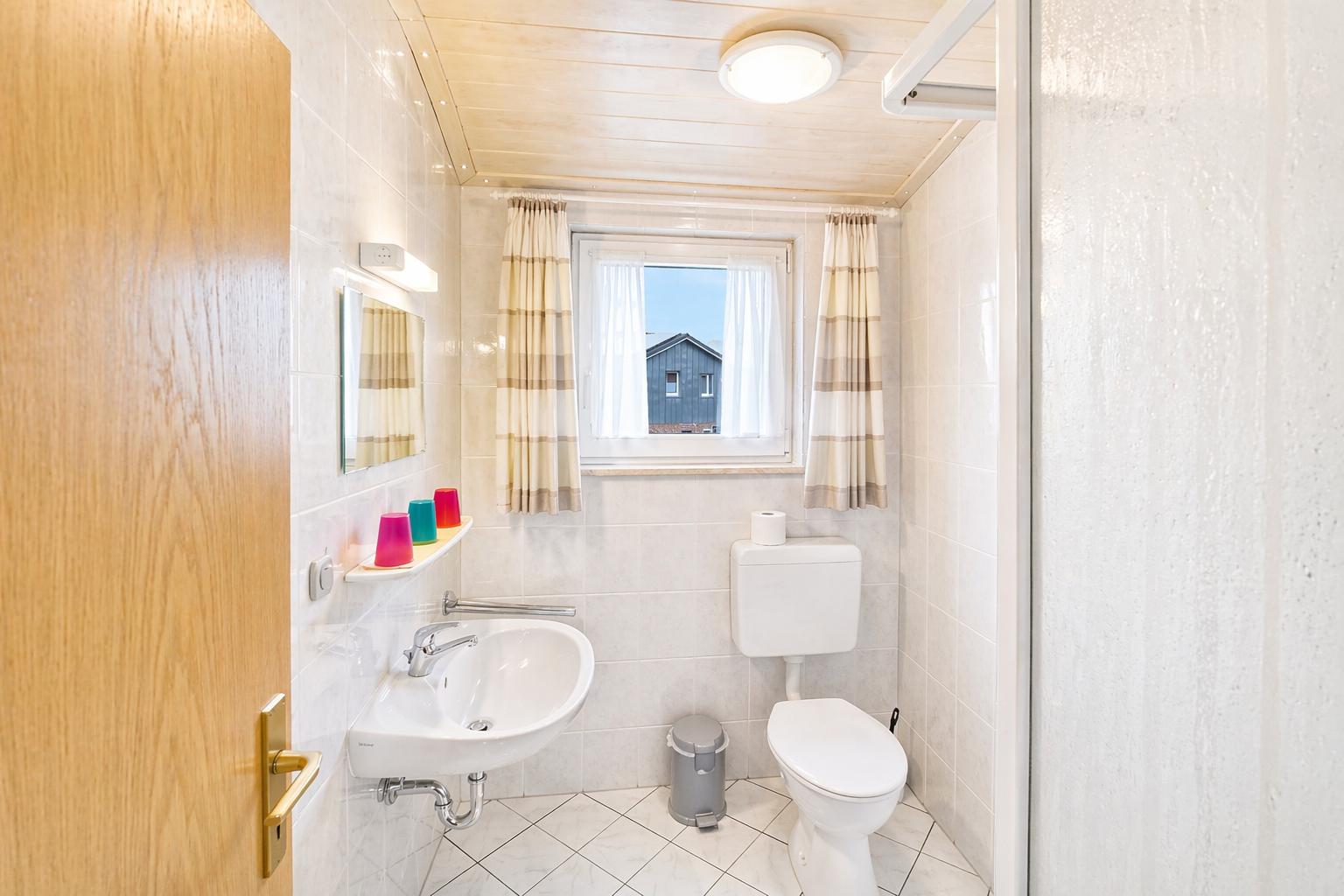 Badezimmer mit Waschbecken, Toilette und Fenster mit Blick.