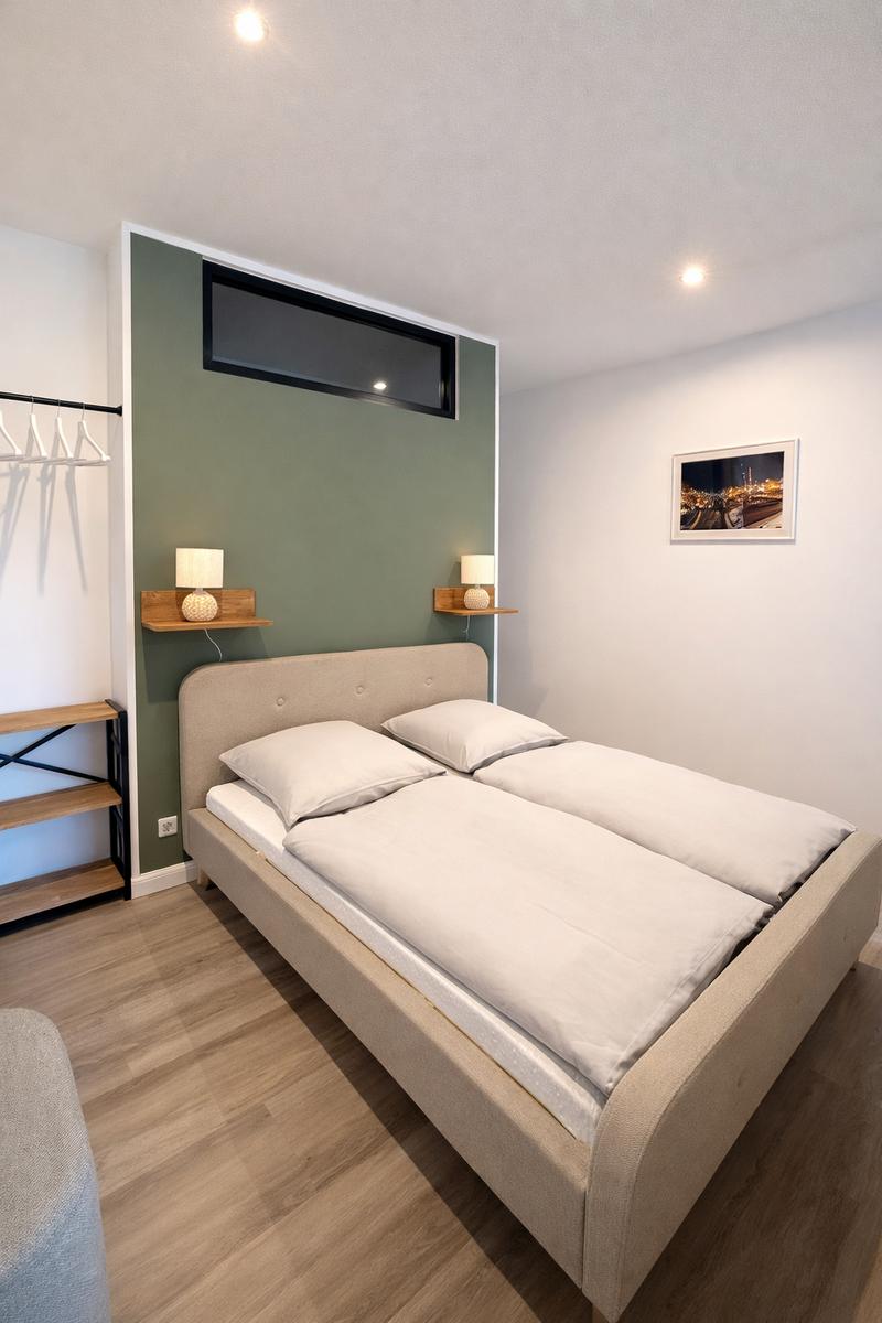 Schlafzimmer mit Doppelbett, grüner Wand und integrierten Nachttischen.