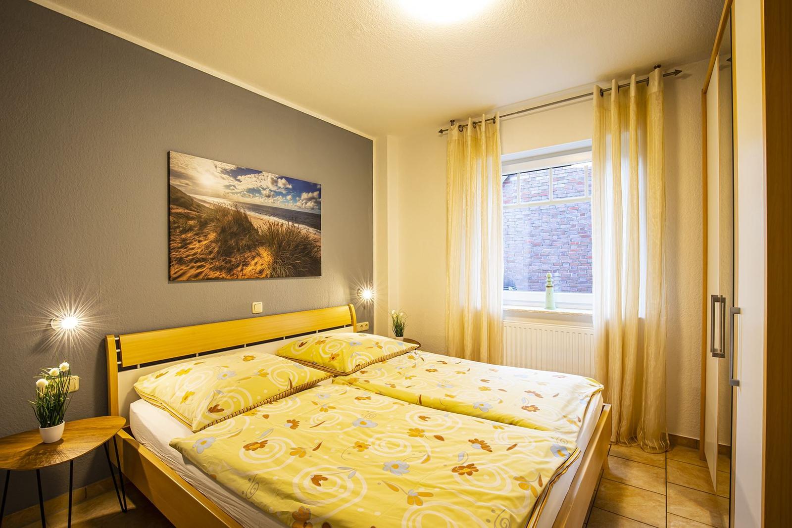Schlafzimmer mit Doppelbett, Fenster und Gardinen. Wandbild und Nachttische.