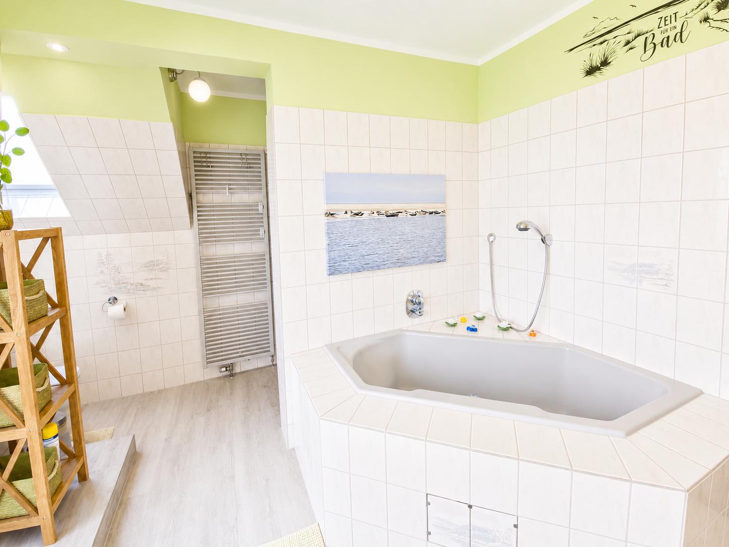 Badezimmer mit Badewanne, Dusche und Holzregal. Wandbild und grüne Farbe.