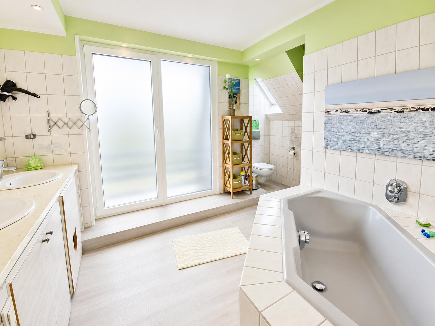 Badezimmer mit Badewanne und Zugang zum Balkon...