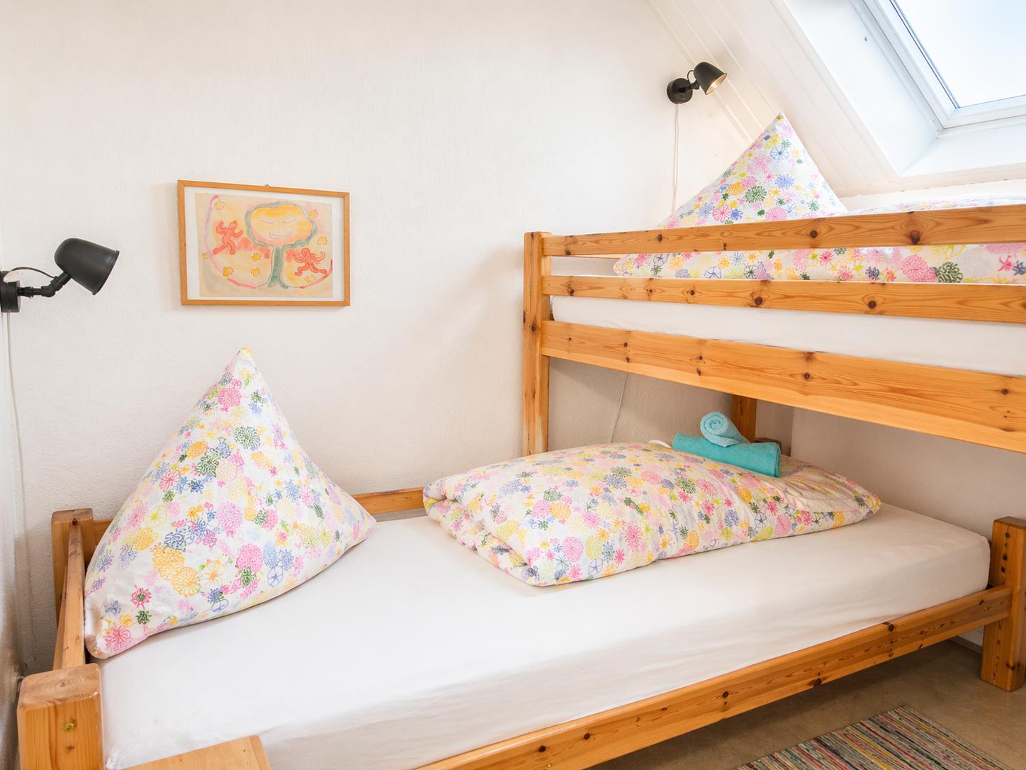 Ein Schlafzimmer mit einem Doppelstockbett aus Holz und einem Fenster.