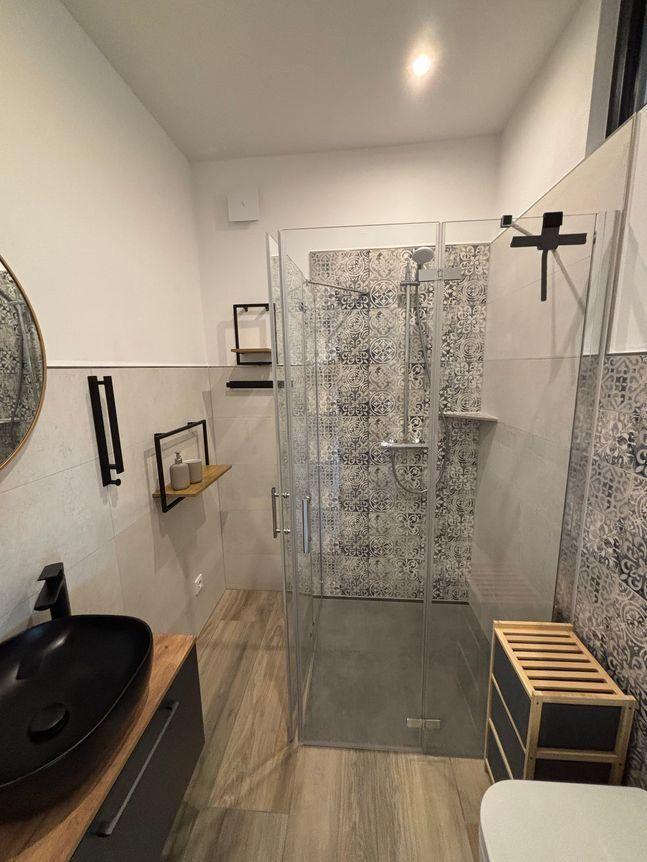 Bad mit Dusche, Waschbecken und Holzregalen