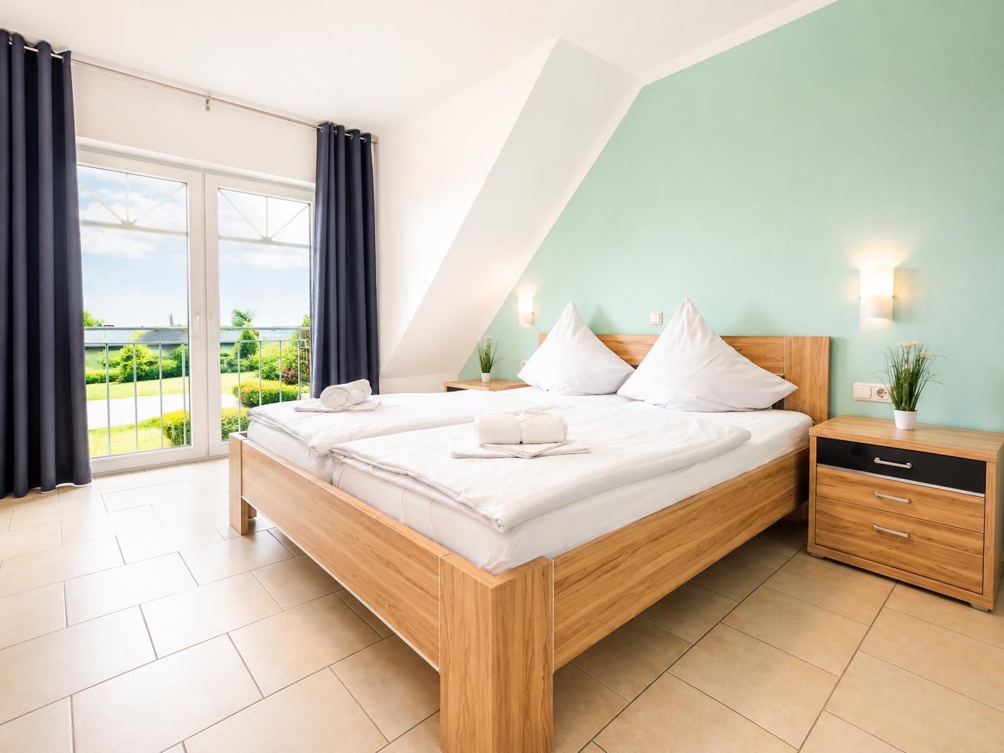 Schlafzimmer mit Doppelbett, Balkon und grüner Wand.