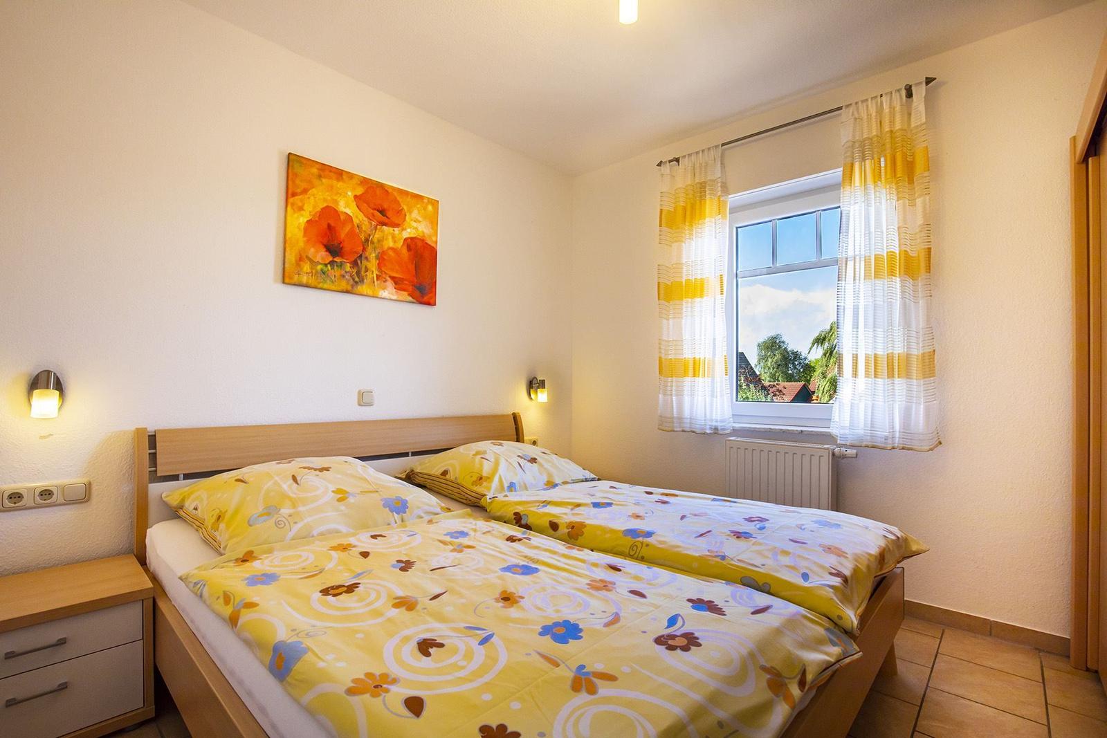Schlafzimmer mit Doppelbett, Fenster und Wandbild.