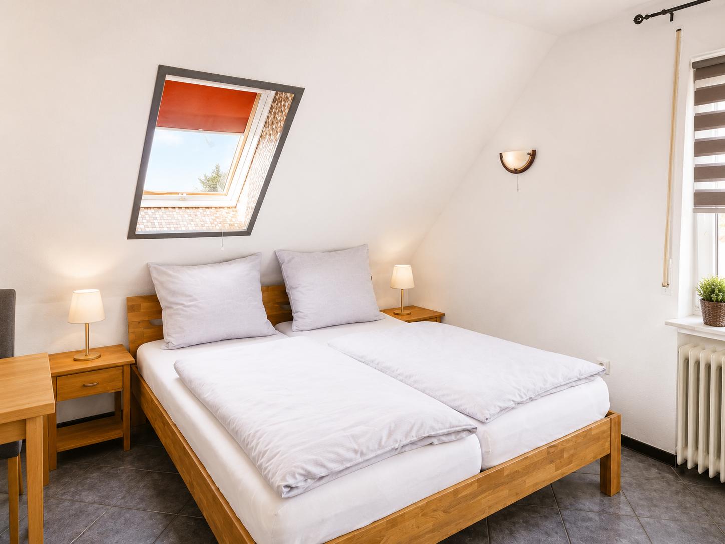 Schlafzimmer mit Doppelbett, zwei Nachttischen und Dachfenster.