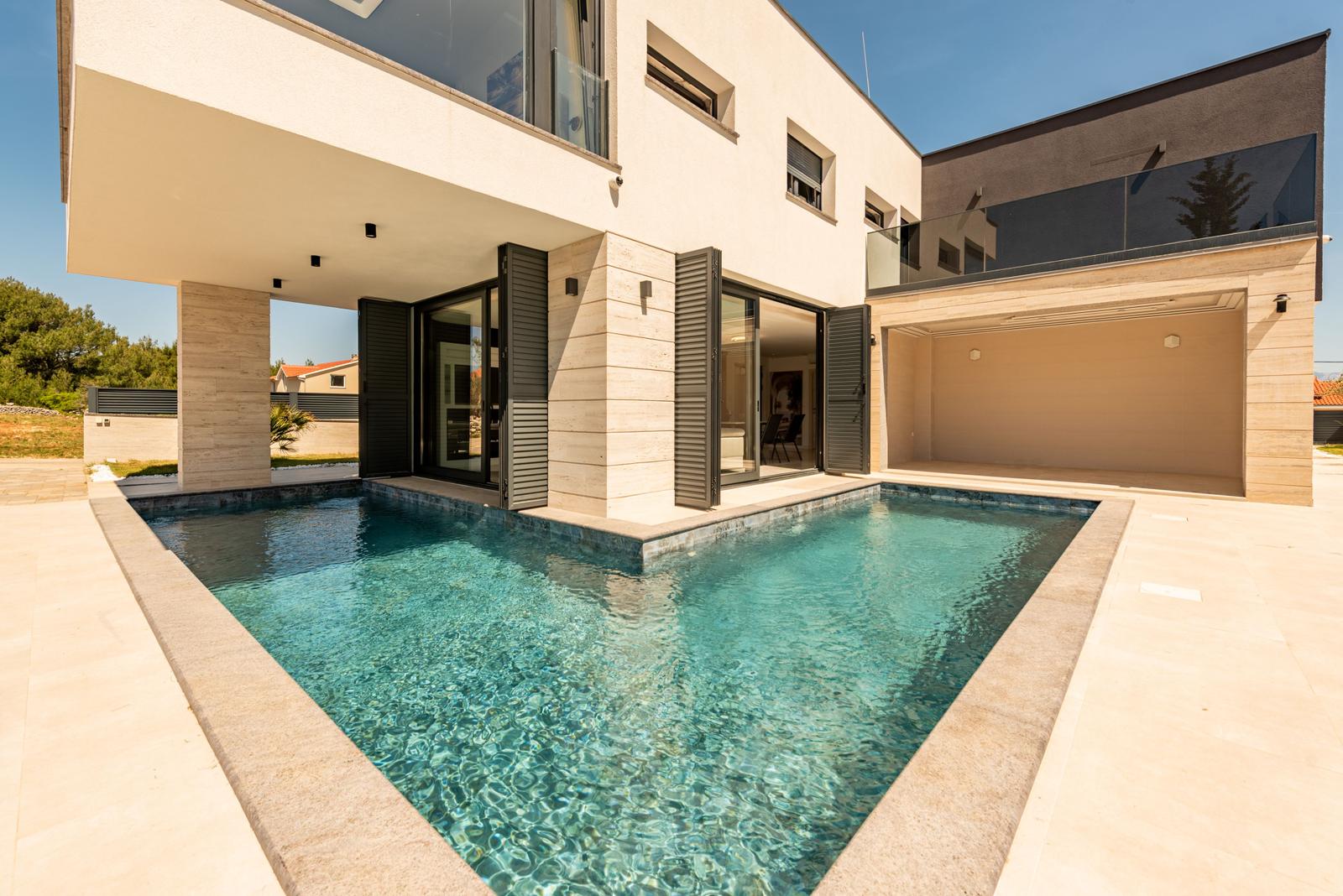 Moderne Villa mit Pool und Terrasse. Glasfronten öffnen sich zum Außenbereich.