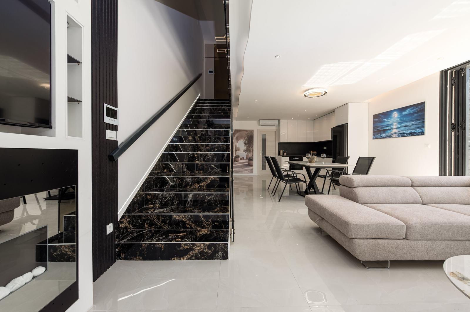 Modernes Wohnzimmer mit schwarzem Marmor-Treppenhaus und grauem Sofa.